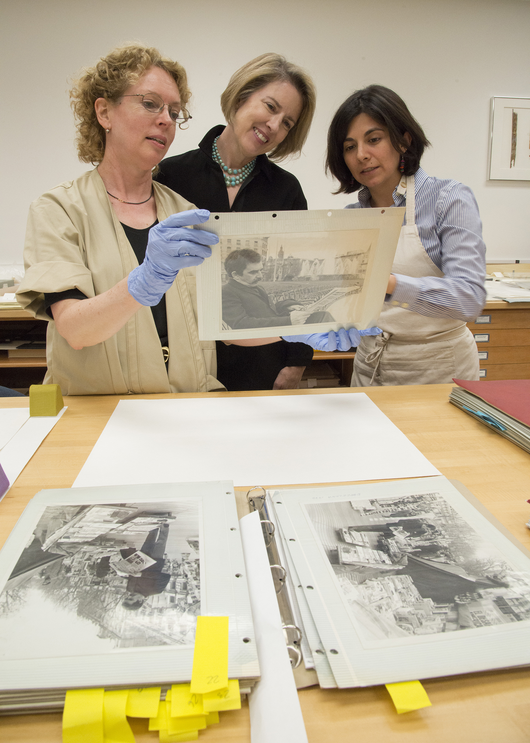 Conservators Barbara Brown (L) and Diana Diaz (R) with Dr. Ellen Cunningham-Kruppa, Associate Director and Head, Conservation and Preservation Division, discussing issues of photographs stuck to "magnetic" album pages. Image courtesy of Harry Ransom Center.