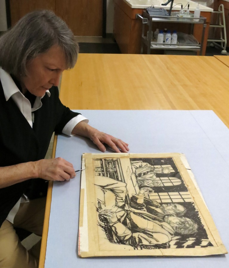 Boyd carefully examines the damages of an item from the Woodward and Bernstein collection, 2016, courtesy of Boyd.