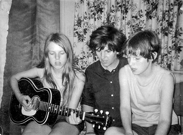 Young woman playing guitar for mother and brother