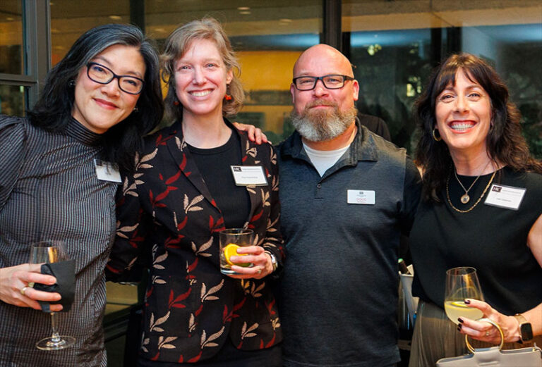 Four people at a party holding drinks