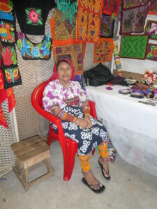 Kuna Indian woman with her molas on wall behind her - courtesy of Marcia Arn