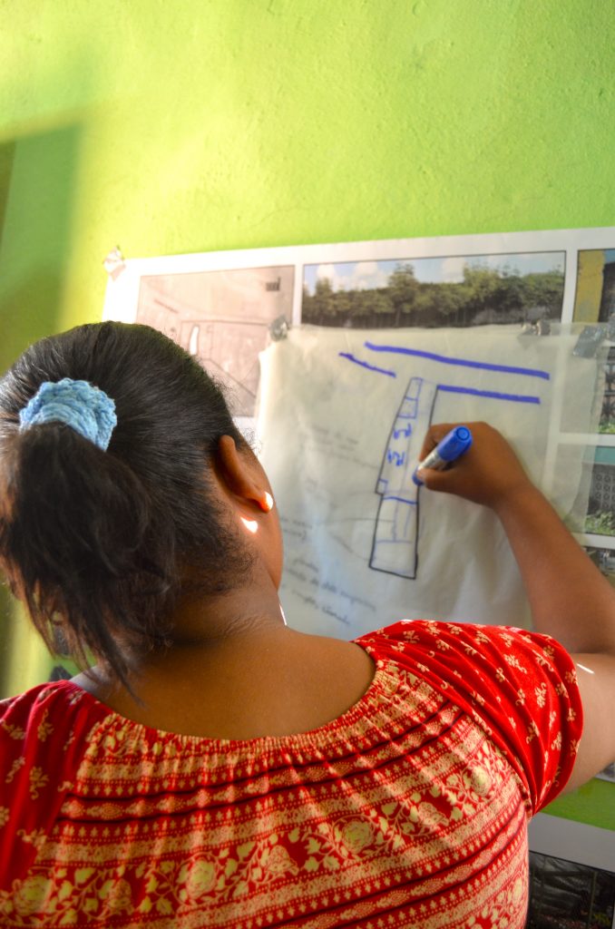 A member of Mujeres Unidas uses trace paper during a participatory design workshop to communicate her vision for the organization's newly acquired land on a busy commercial avenue. 