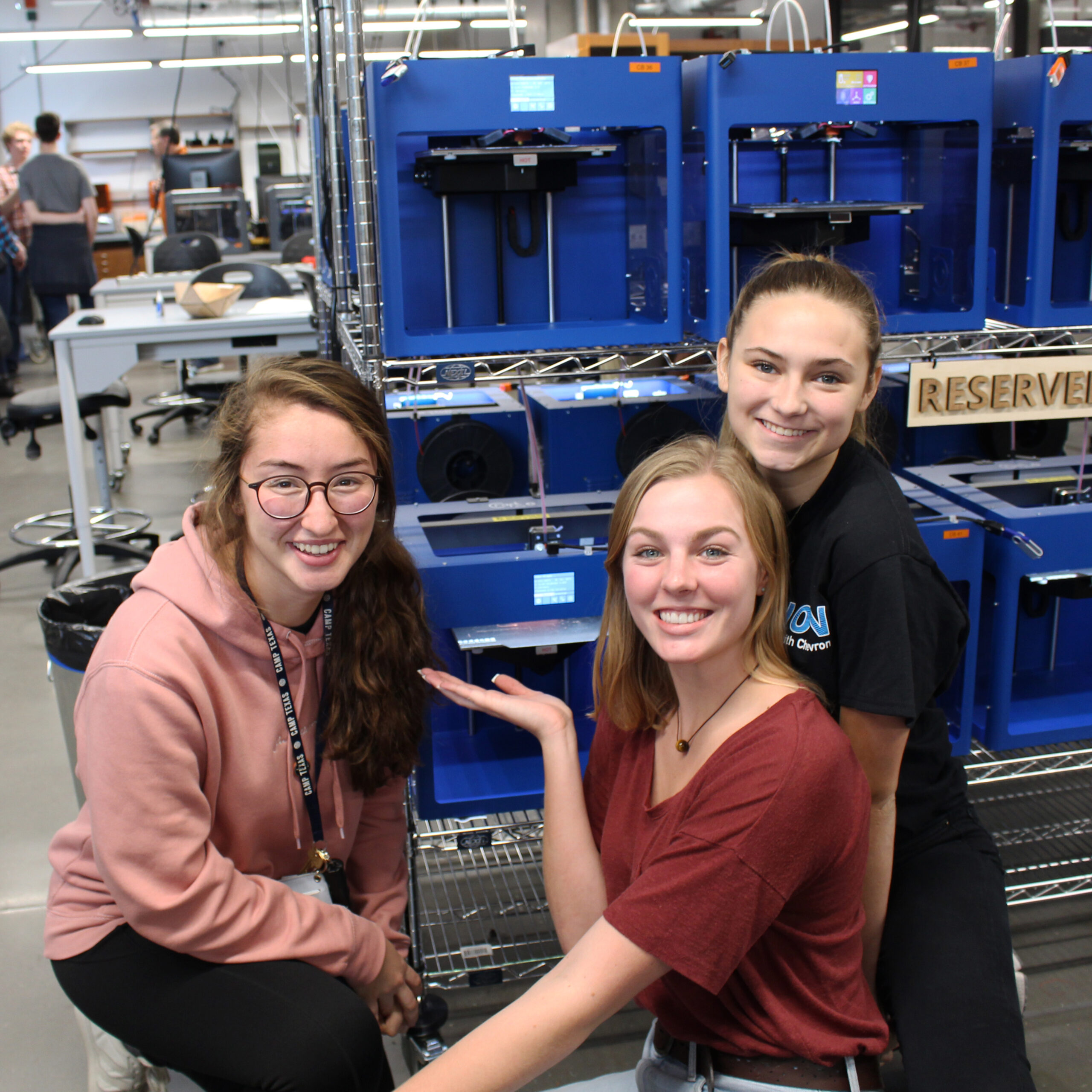 Three engineers posing with a 3D printer