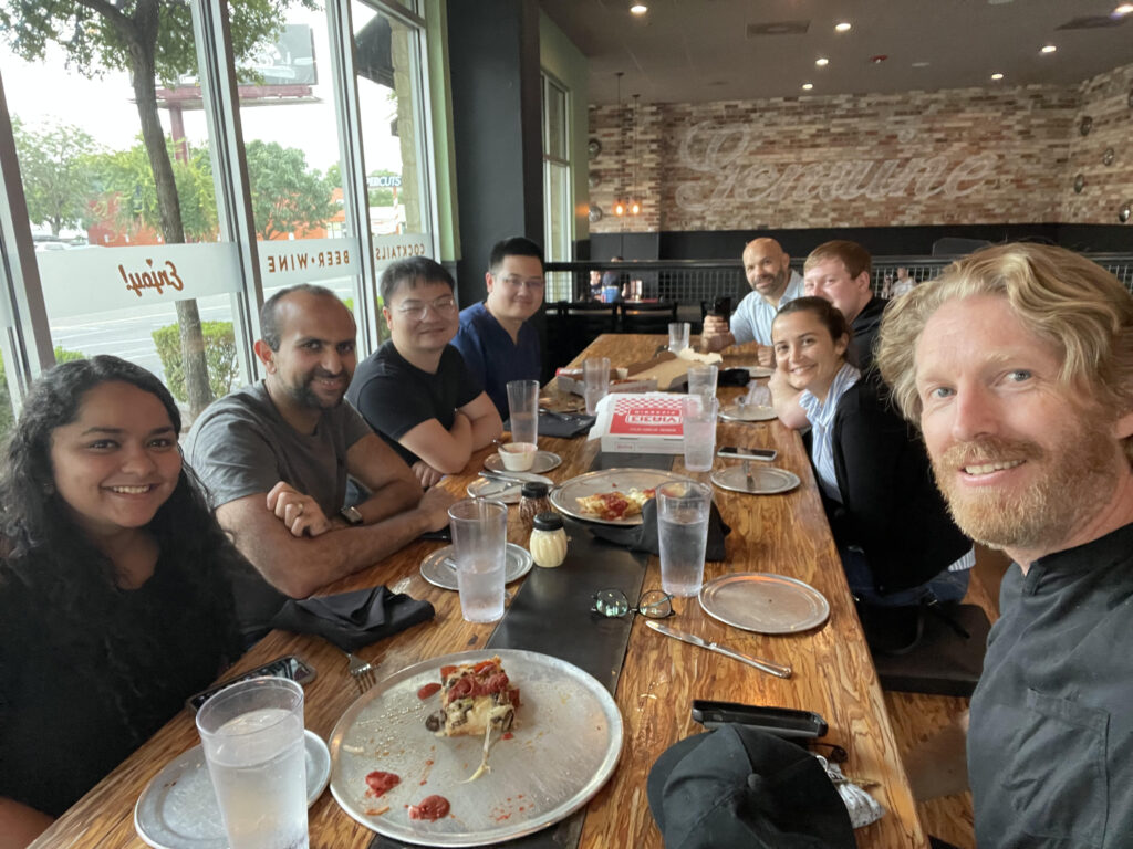 Lab social event with seven lab members and Dr. Smyth seated at a long restaurant table.