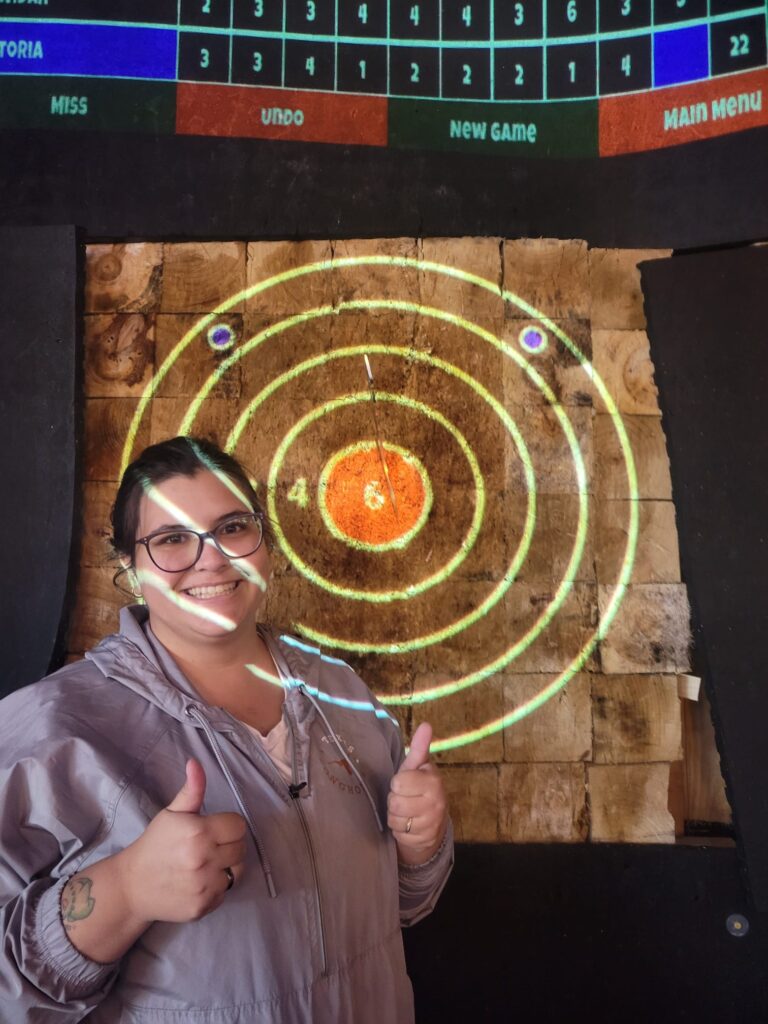 Visiting Ph.D. student from Brasil, Victoria, gives thumbs up after throwing axe.