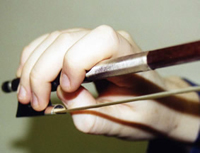 Proper violin / viola bow hand position, showing the fingers curved over the bow and the thumb positioned on the frog of the bow.