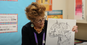 Photo of Liz Abrahams reviewing artwork with elementary students