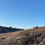 Top of Enchanted Rock and hills beyond, with clear, blue sky.