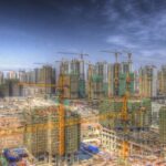 Illustration of cityscape with multiple cranes erecting high-rise buildings.