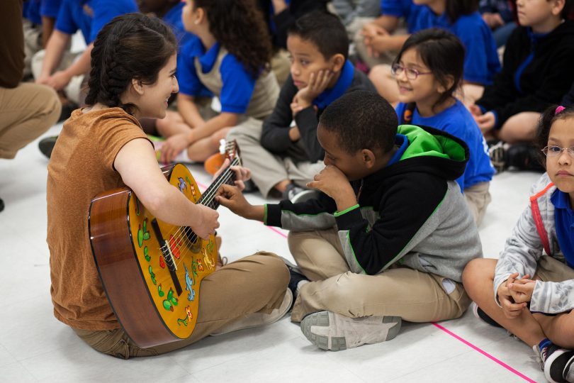 woman playing guitar for children