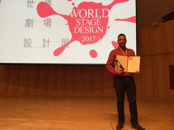 man with award in front of screen