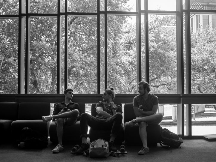 three students eating lunch in front of windows