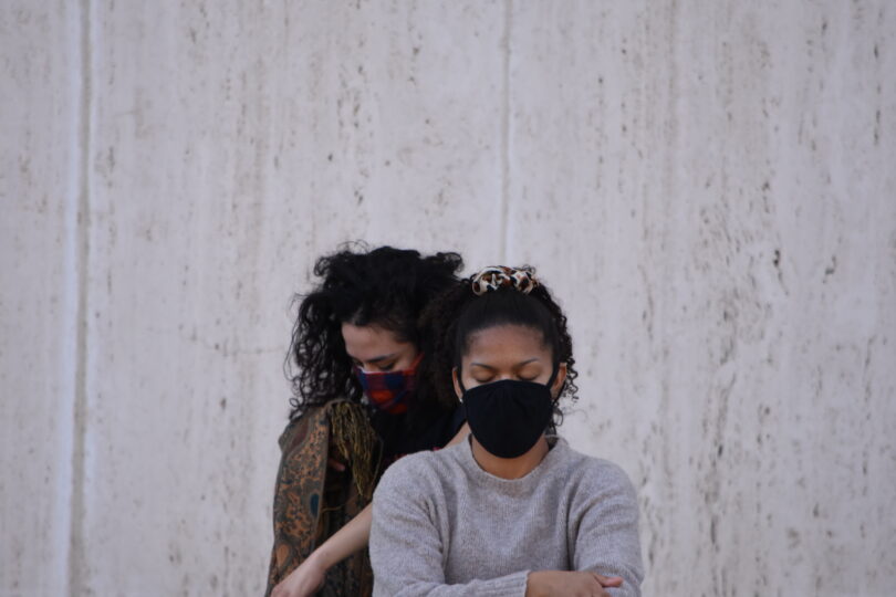 two women with masks standing close to one another