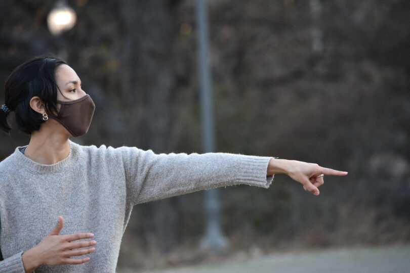 woman directing dancers with brown mask on