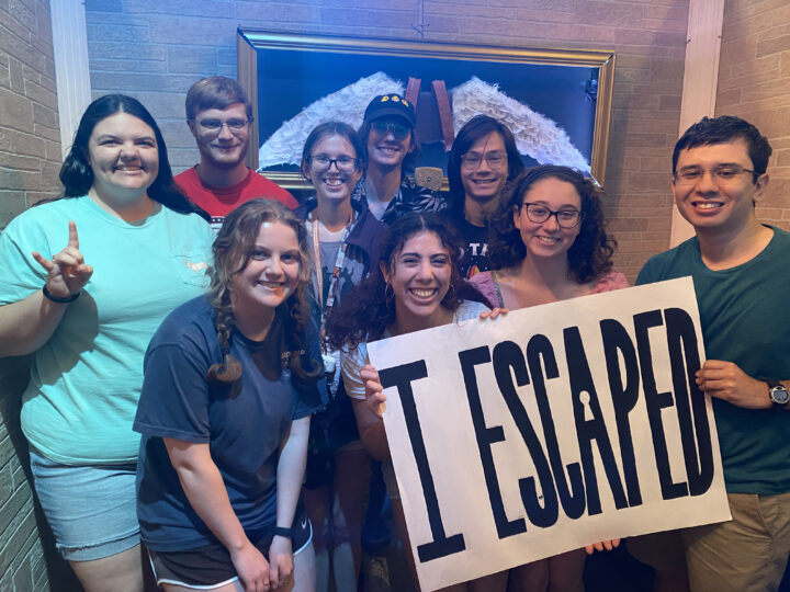 group of collaborators pose in an escape room that they created