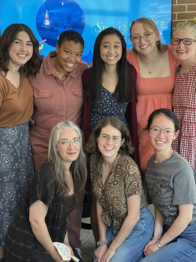 eight collaborators pose in front of a backdrop for SPELLS OF THE SEA