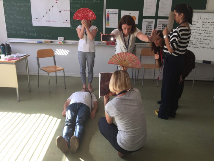 six educators create an image from a story, posing with fans, flashlights and posters