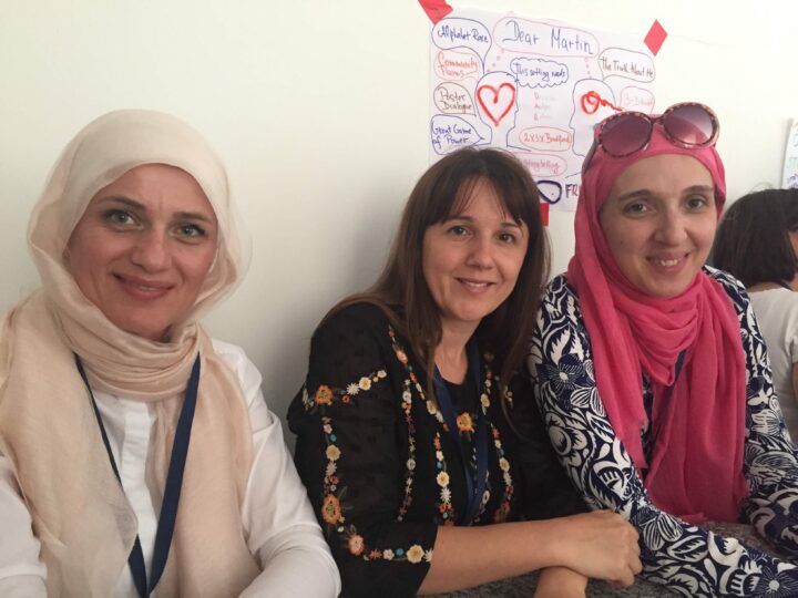 three teachers from Bosnia and Herzegovina pose in front of a visual diagram they created