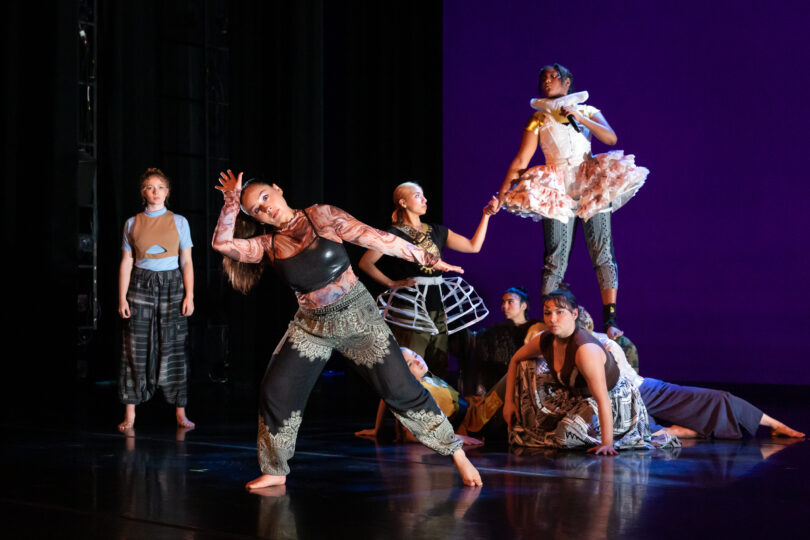 Dancers dressed in renaissance style clothing pose on stage