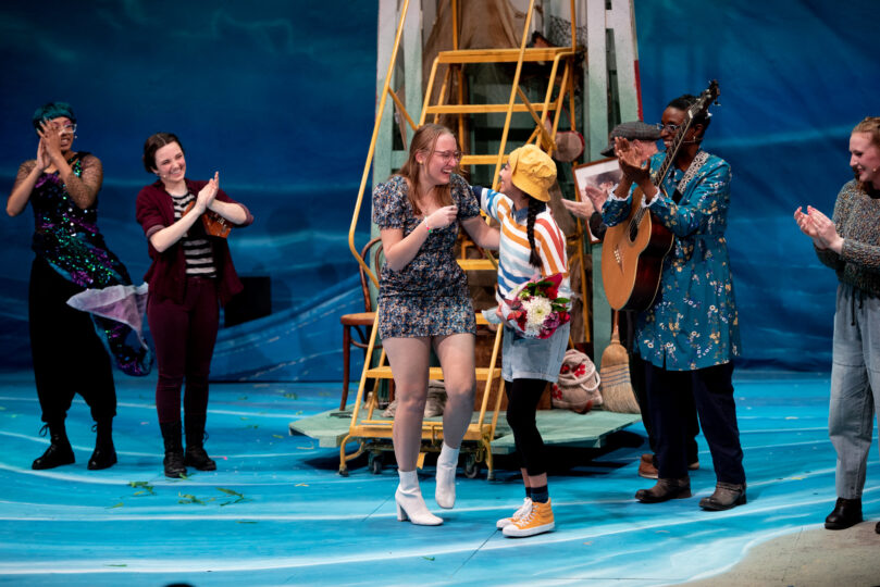 Anna Pickett and Guinevere "Gwenny" Govea embrace excitedly, standing on stage after the world premiere of SPELLS OF THE SEA