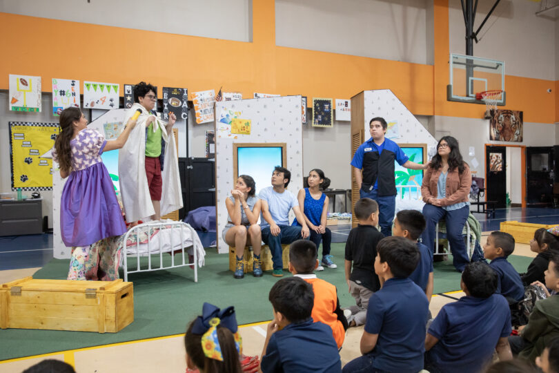 Seven actors perform the final scene of THE SMARTEST GIRL IN THE WORLD, while an audience of elementary school students watches