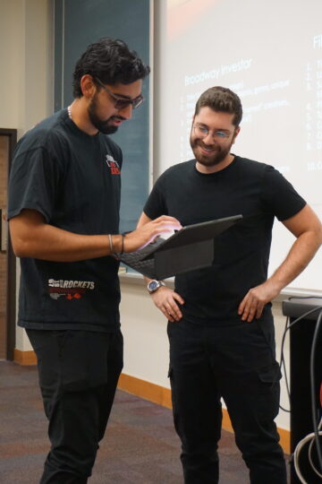 David Treatman smiles while looking at a student's project on their tablet
