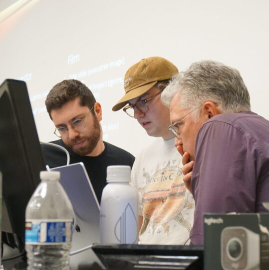 David Treatman and Dr. Paul Bonin-Rodriguez look at a student's project on their laptop