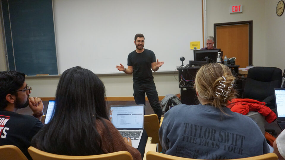 David Treatman presents a lecture, standing in front of a classroom of students