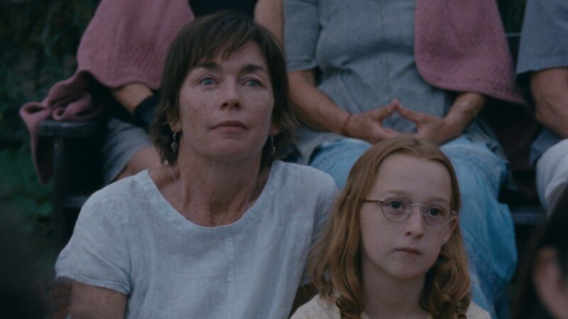 A scene from the film JANET PLANET featuring a mother and daughter sitting next to each other and looking forward