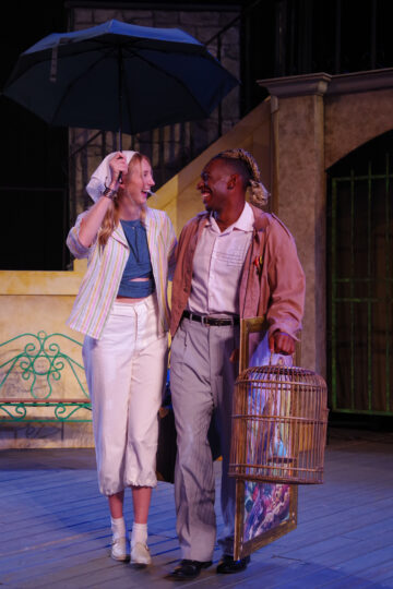 Sophie Anne Miller and Tevin Davis perform in a scene, walking and laughing together under an umbrella