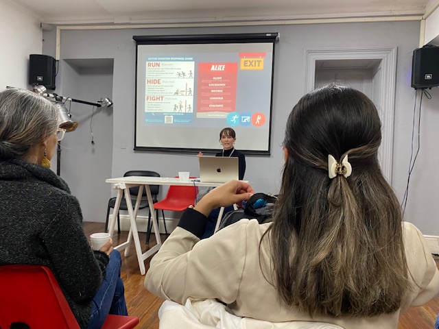 Shannon Woods presents on a panel, with a presentation screen behind her and audience in front of her