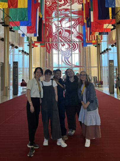 Three alumni, one student and one faculty member pose together in the Hall of Nations at the Kennedy Center