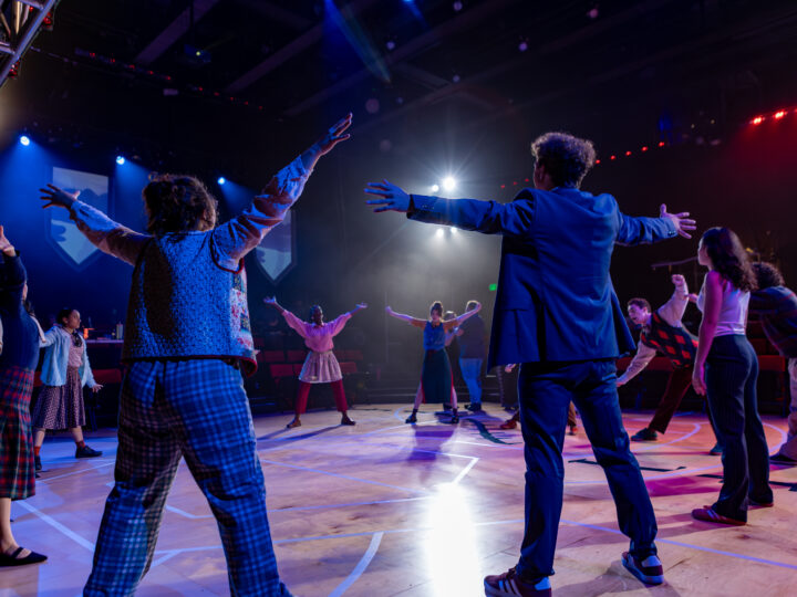 The cast of Great Lakes stands with their arms outstretched, stretching together in a large circle.