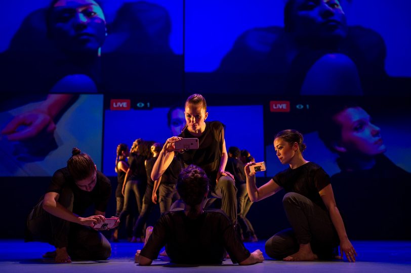 performers sitting on stage looking at their phones