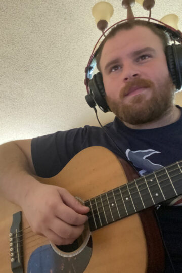 man playing guitar with headphones on
