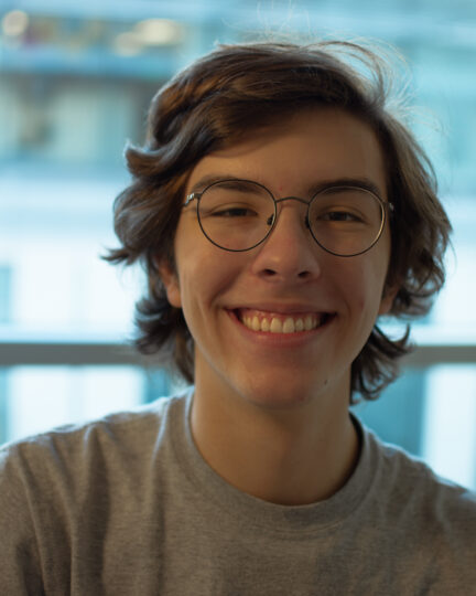 man with blonde hair and glasses wearing a gray t-shirt