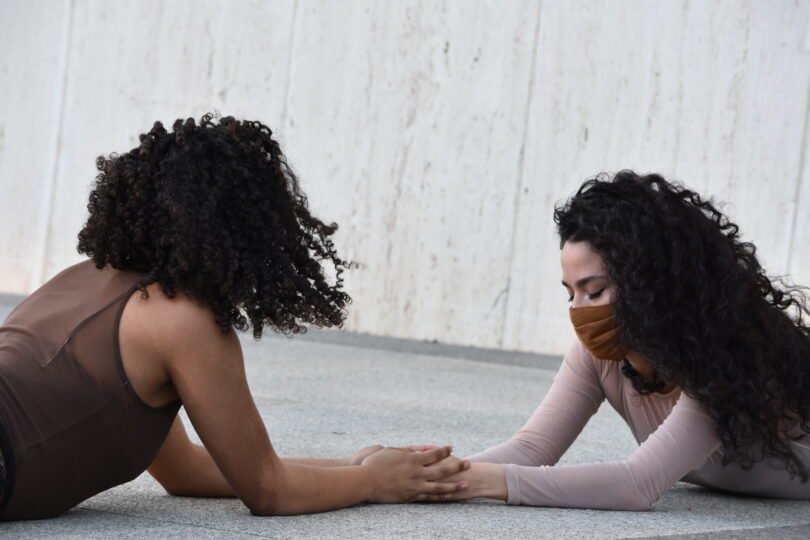 two dancers on the ground holding hands