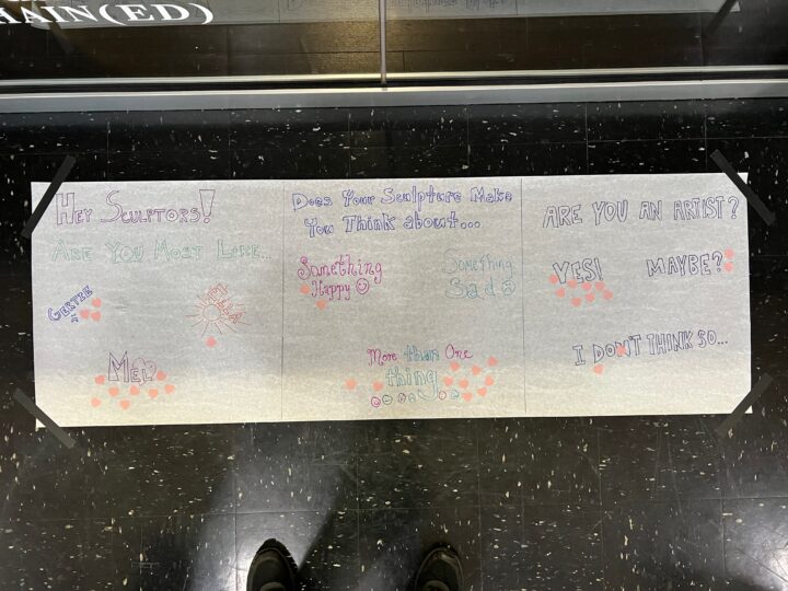 A long piece of paper with prompts written in block letters and little paper hearts placed over different answers