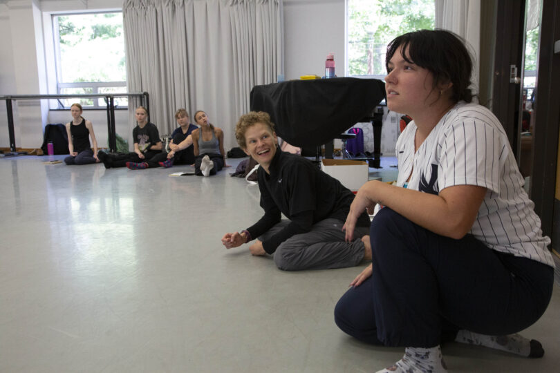 Sabrina Blackwelder gives a suggestion to a group of summer camp participants in a large dance studio, while Leah Cox looks on and smiles