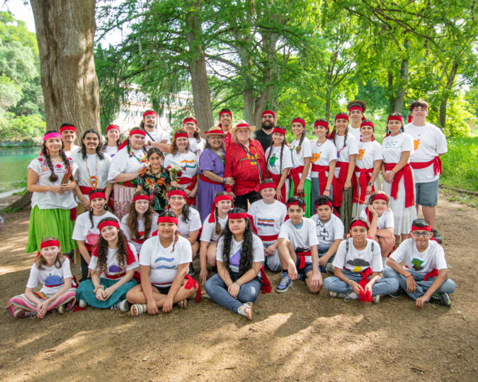 A large group of people wearing red scarves around their foreheads and waists during the Indigenous Cultures Institute Summer Youth Encounter