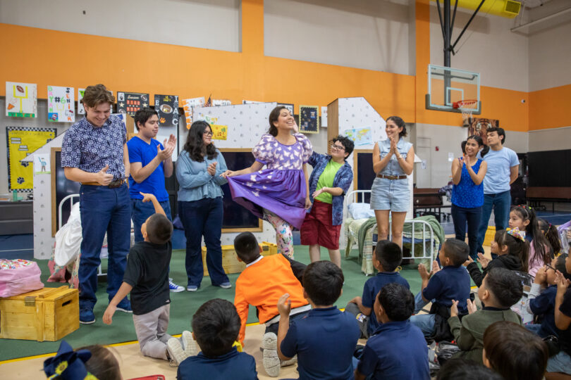 The cast of THE SMARTEST GIRL IN THE WORLD bows in front of an excited audience of elementary school students