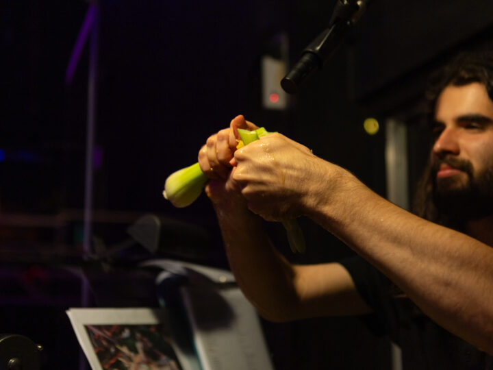 Cooper Smithers, sound designer and live Foley performer, cracks open a stalk of celery. Juices flow down his hand.