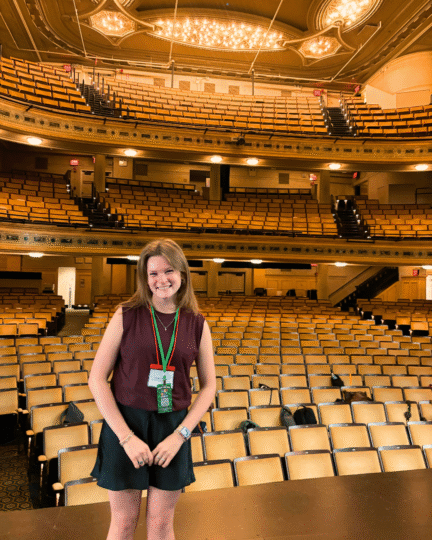 Photo of Sophia Campbell standing in front of a large theatre auditorium