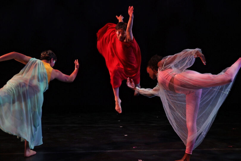 three dancers perform in DREAMS IN THE MIST, one leaping and reaching outward