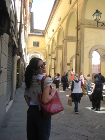 woman smiling over her shoulder walking down a florentine street