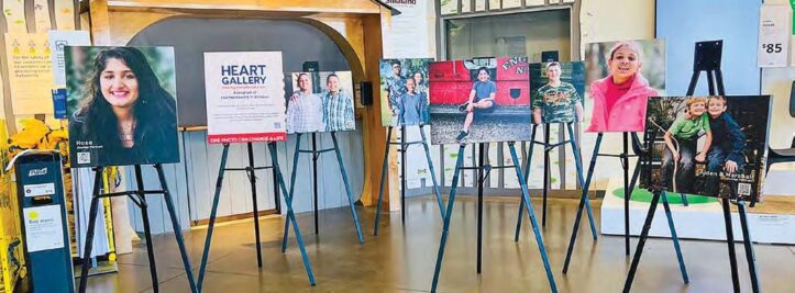 Portraits of children and teens waiting for adoption displayed on easels at a Heart Galleries of Texas exhibit, with the Heart Gallery logo visible.
