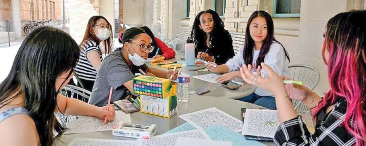 Students seated around a table engaged in an arts-based activity — part of mental health and humanities research.