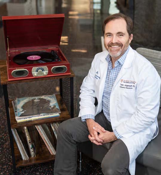 Dr. Tyler Jorgensen of Dell Medical School poses with a vinyl player and vinyl records