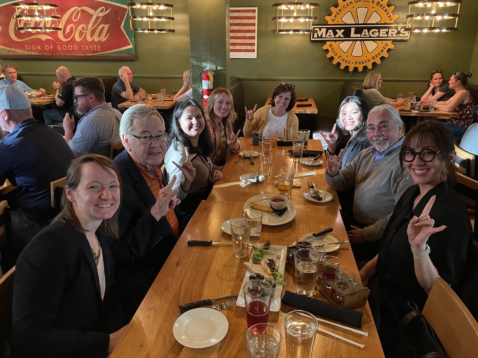 Group photo at a lunch, people giving the Horns logo.