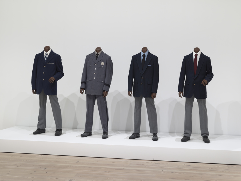 Four headless mannequins positioned on a dais and adorned in different male business suits